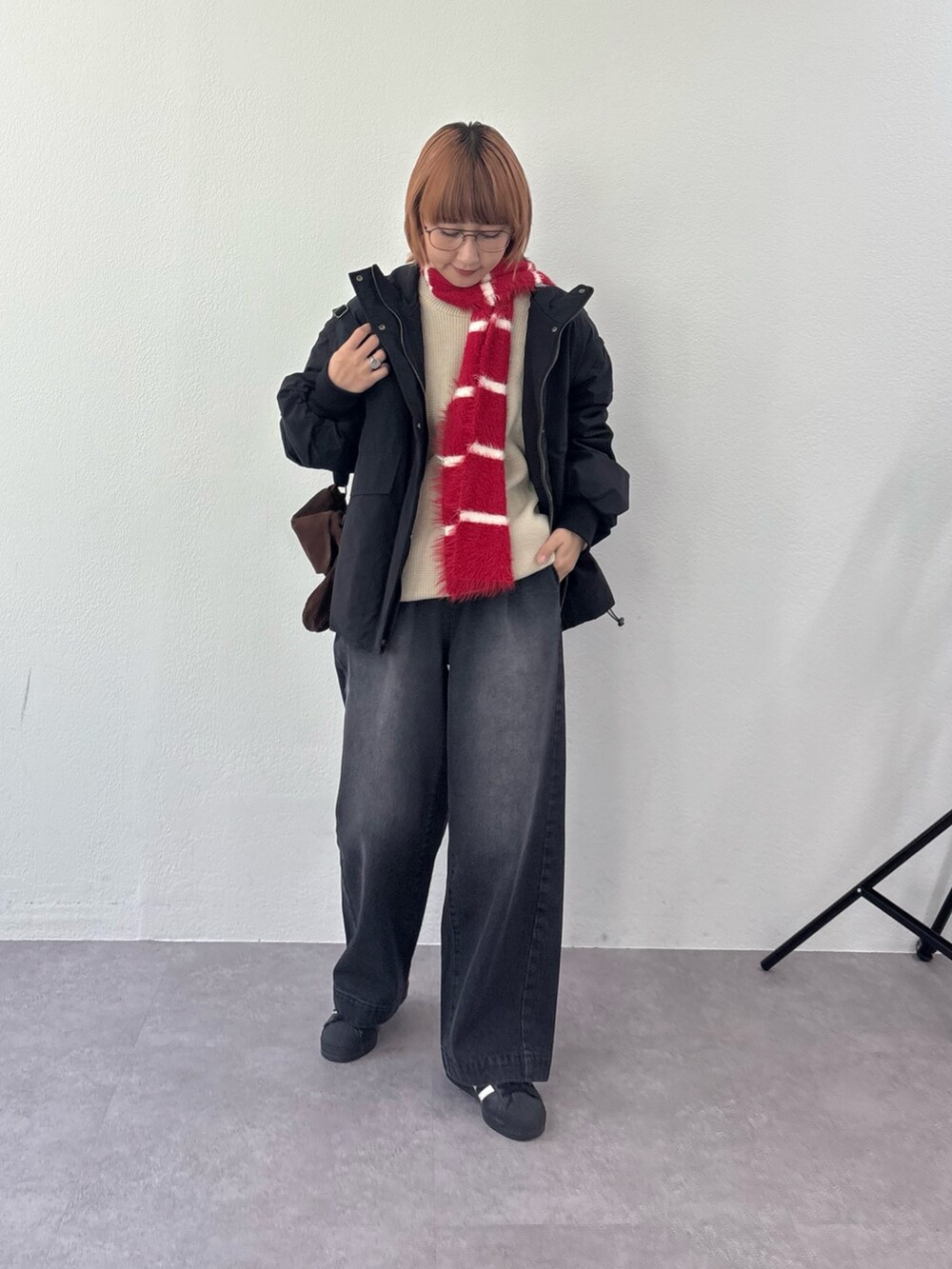 ブラック系のブルゾン、ホワイト系のニット/セーター、ブラック系のデニムパンツを着用したレディースの秋コーディネートの2枚目の写真