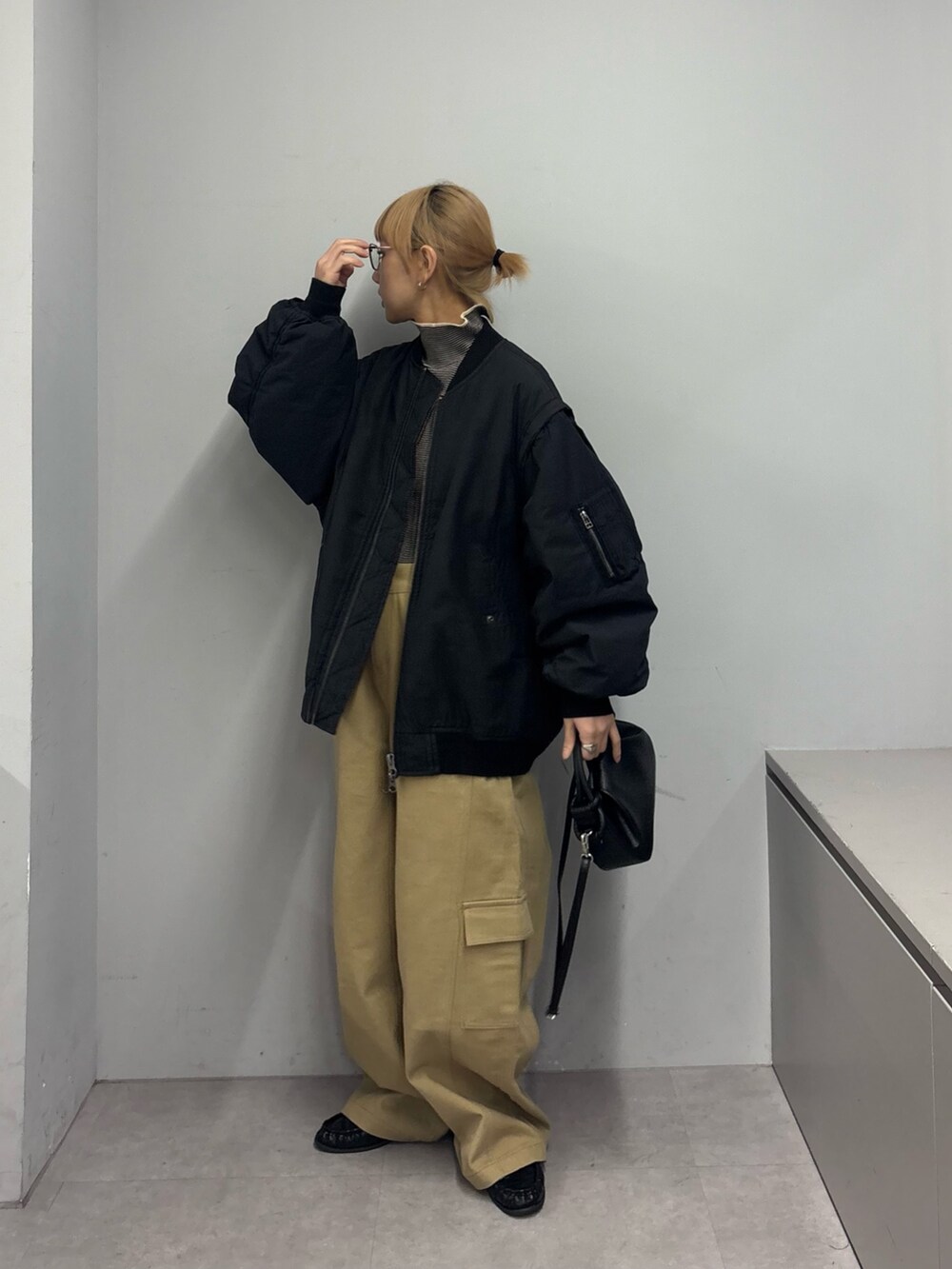 ブラック系のMA-1、ホワイト系のニット/セーター、ベージュ系のカーゴパンツを着用したレディースの冬コーディネートの3枚目の写真