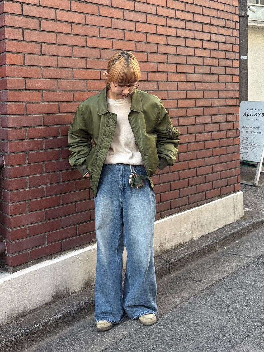 グリーン系のMA-1、ブルー系のデニムパンツ、ホワイト系のニット/セーターを着用したレディースの冬コーディネートの3枚目の写真