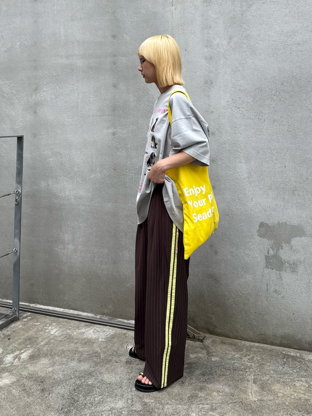 グレー系のTシャツ/カットソー、ブラック系のサンダル、ブラウン系のスラックスを着用したレディースの春コーディネートの2枚目の写真