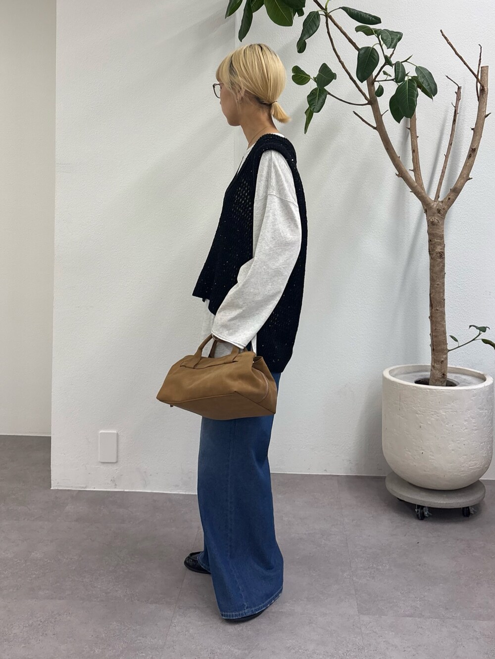 ブラック系のベスト、グレー系のTシャツ/カットソー、ブルー系のデニムパンツを着用したレディースの春コーディネートの3枚目の写真