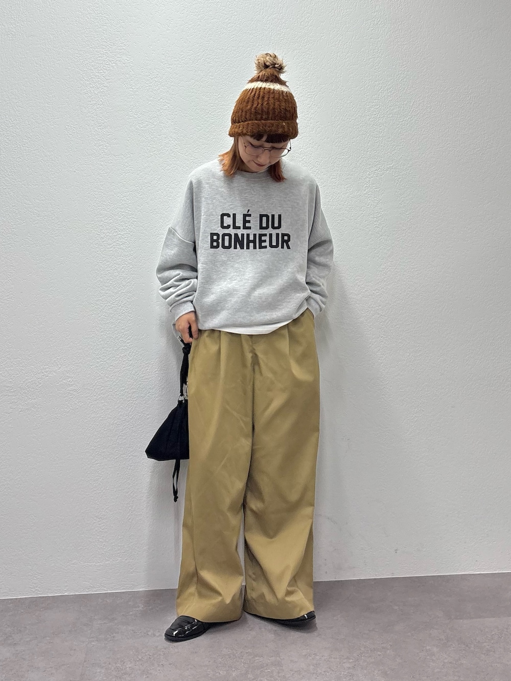 グレー系のスウェット、ベージュ系のデニムパンツ、ブラック系のショルダーバッグを着用したレディースの秋コーディネートの2枚目の写真