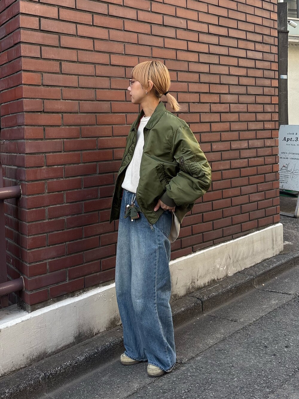 グリーン系のMA-1、ブルー系のデニムパンツ、ホワイト系のニット/セーターを着用したレディースの冬コーディネートの2枚目の写真