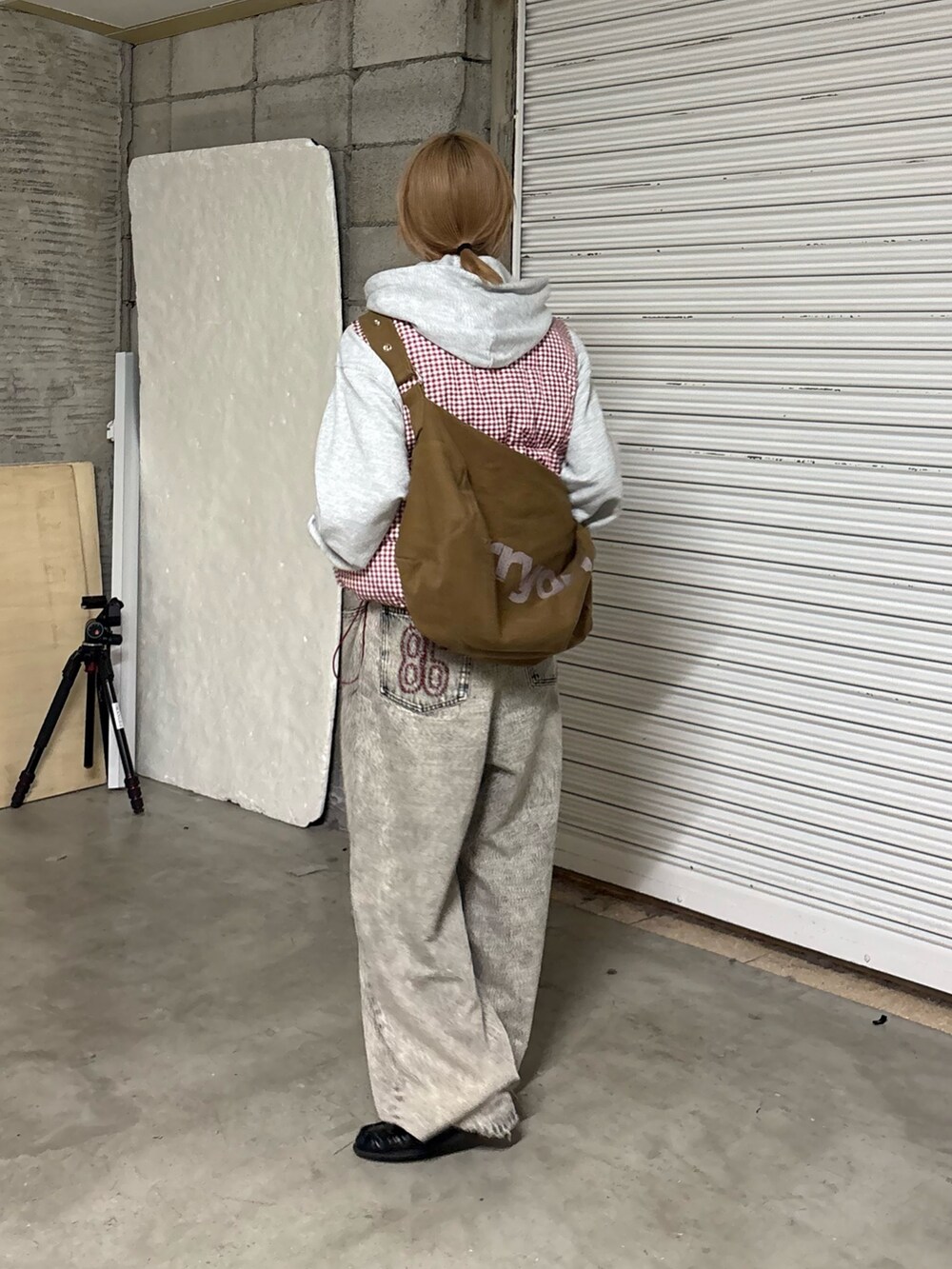 グレー系のパーカー、レッド系のベスト、ブラウン系のトートバッグを着用したレディースの冬コーディネートの2枚目の写真