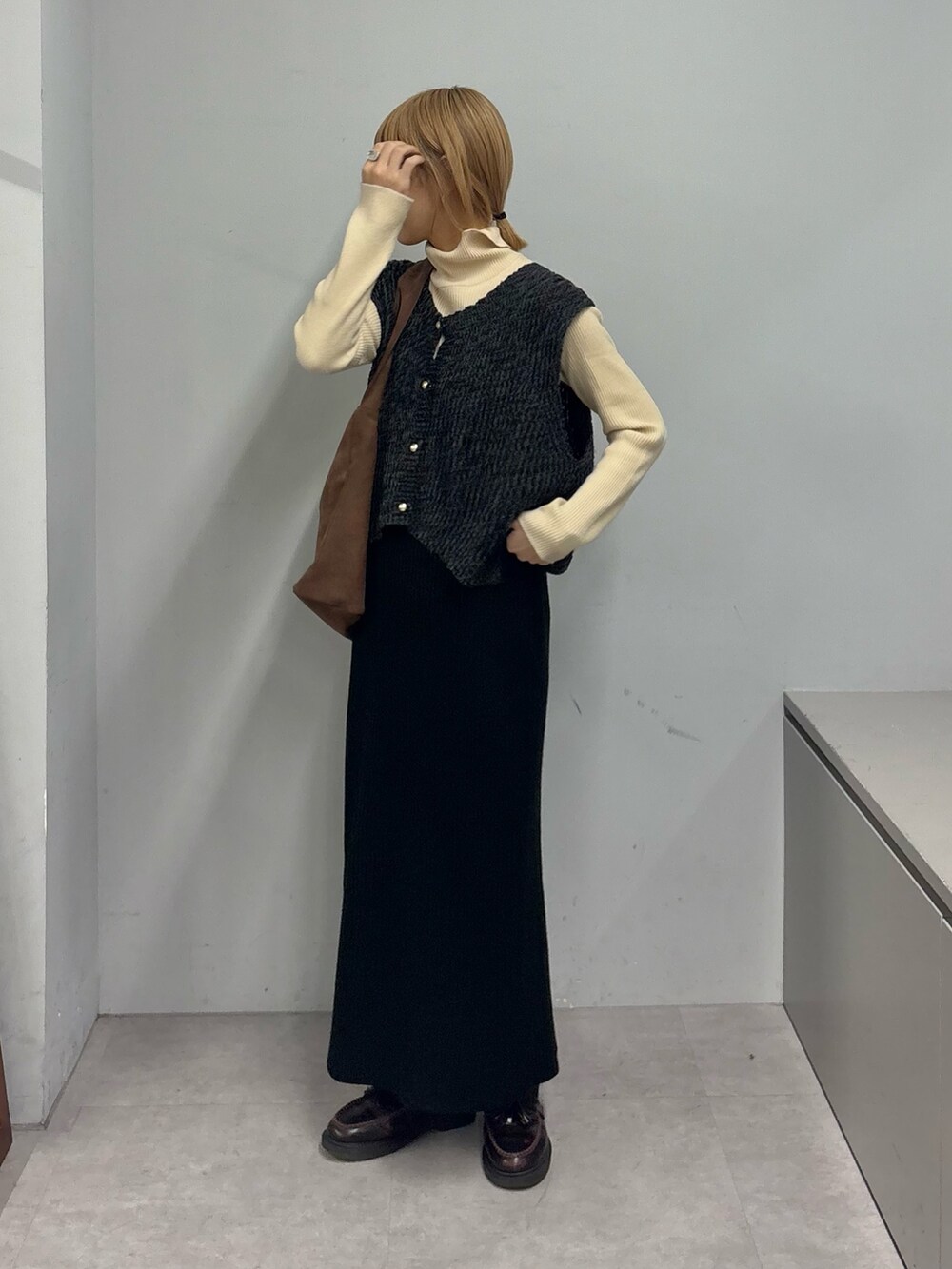 ホワイト系のニット/セーター、ブラック系のベスト、ブラック系のスカートを着用したレディースの冬コーディネートの3枚目の写真