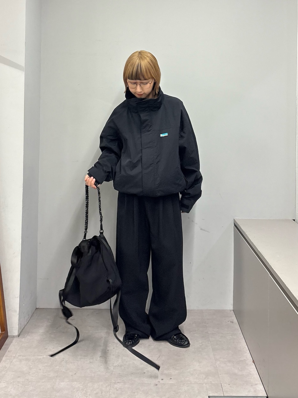 ブラック系のナイロンジャケット、ブラック系のスラックス、ブラック系のトートバッグを着用したレディースの冬コーディネートの2枚目の写真