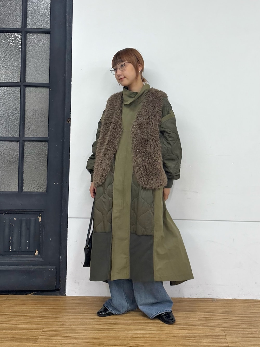 グリーン系のモッズコート、ブルー系のデニムパンツ、グレー系のハンドバッグを着用したレディースの秋コーディネートの2枚目の写真