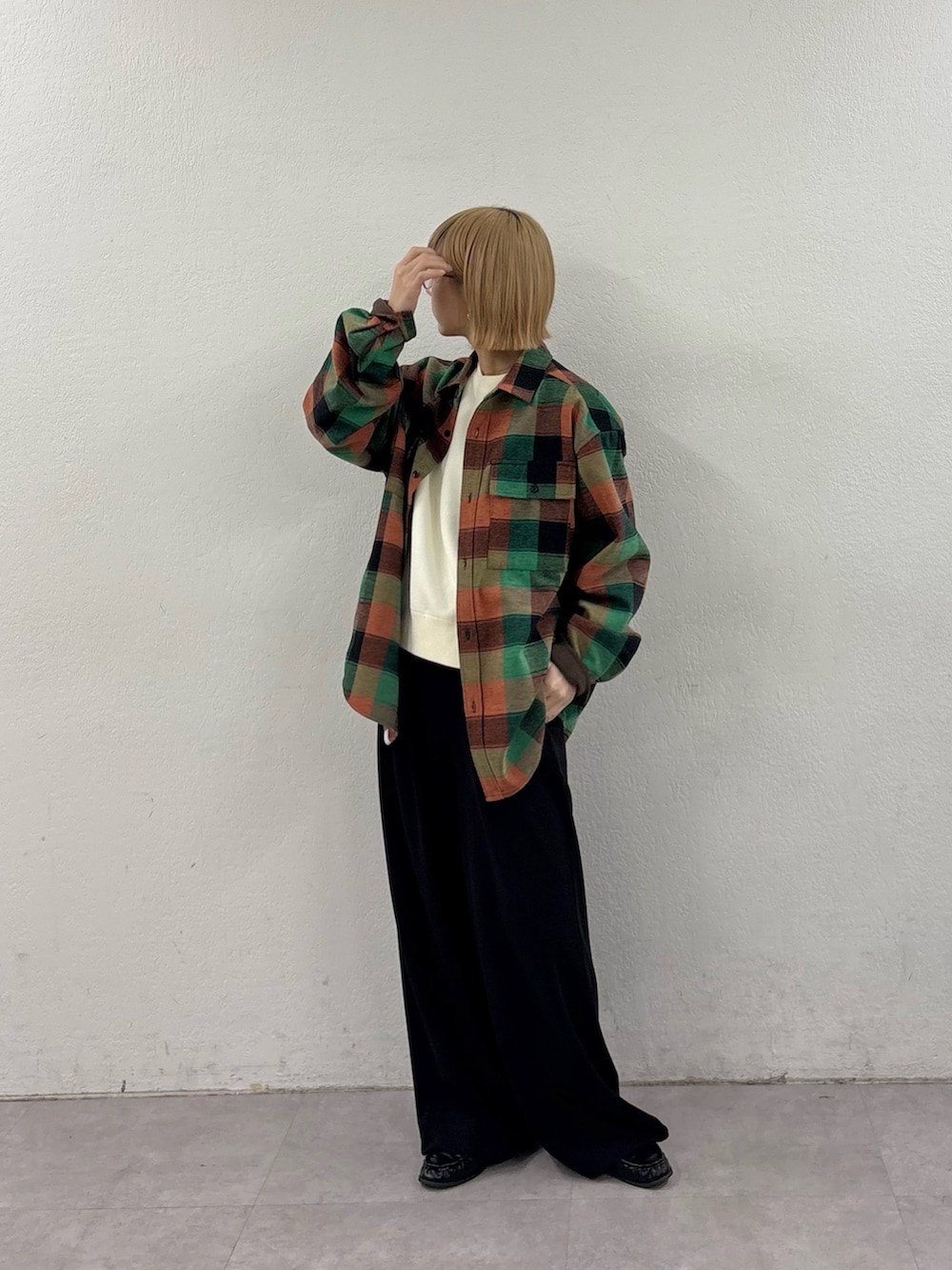 ブラック系のスラックス、ホワイト系のニット/セーター、グリーン系のシャツ/ブラウスを着用したレディースの冬コーディネートの2枚目の写真