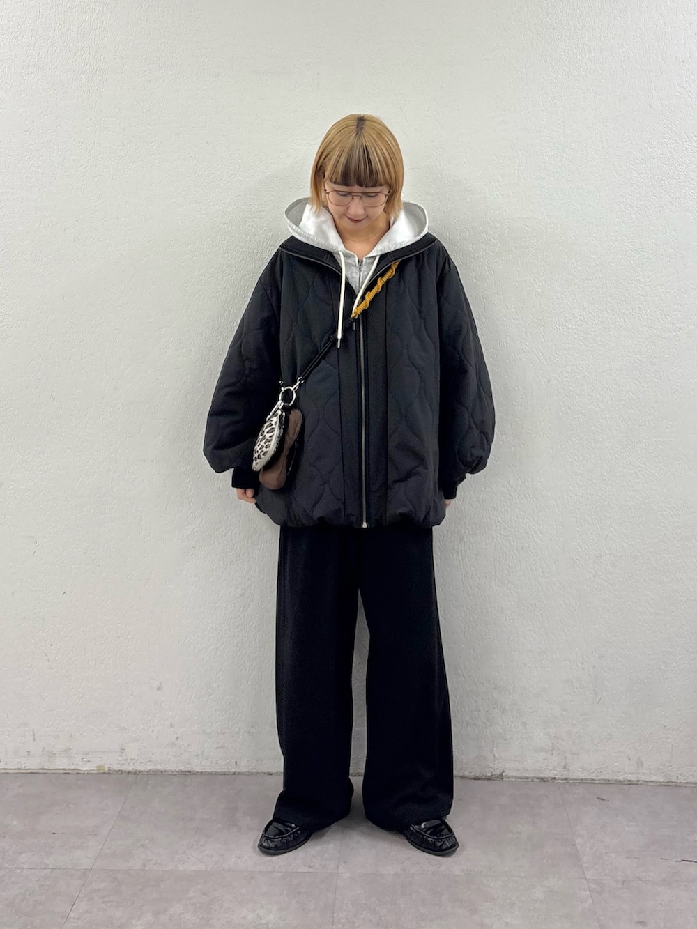 グレー系のパーカー、ブラック系のブルゾン、ブラック系のスラックスを着用したレディースの冬コーディネートの2枚目の写真