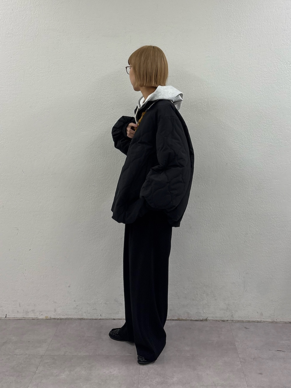 グレー系のパーカー、ブラック系のブルゾン、ブラック系のスラックスを着用したレディースの冬コーディネートの3枚目の写真