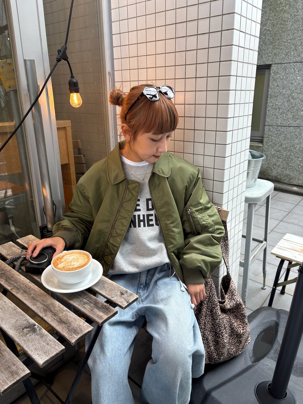 グレー系のスウェット、ブルー系のデニムパンツ、グリーン系のMA-1を着用したレディースの秋コーディネートの2枚目の写真