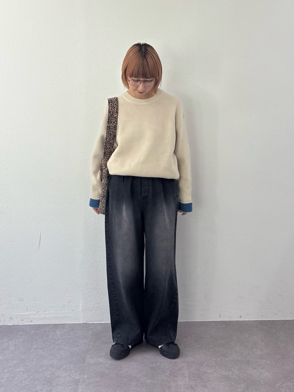 ブラック系のデニムパンツ、ホワイト系のニット/セーター、ベージュ系のトートバッグを着用したレディースの秋コーディネートの2枚目の写真