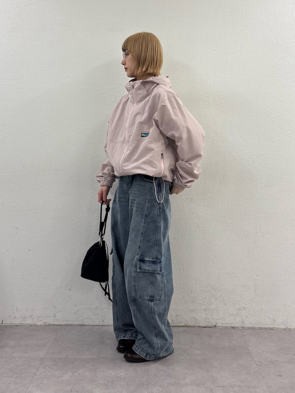 ピンク系のマウンテンパーカー、ブルー系のカーゴパンツ、ブラック系のショルダーバッグを着用したレディースの春コーディネートの2枚目の写真