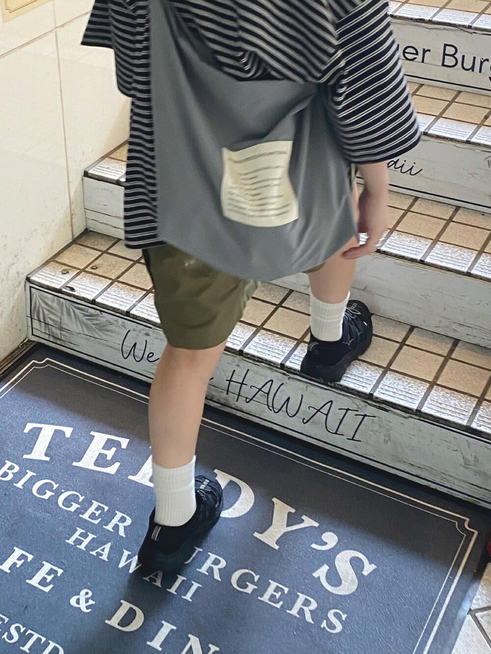 ブラック系のTシャツ/カットソー、グリーン系のカーゴパンツ、ブラック系のスニーカーを着用したレディースの春コーディネートの2枚目の写真