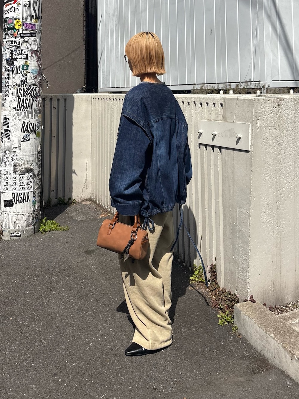 ベージュ系のショルダーバッグ、ブルー系のデニムジャケット、ブラック系のパンプスを着用したレディースの春コーディネートの2枚目の写真