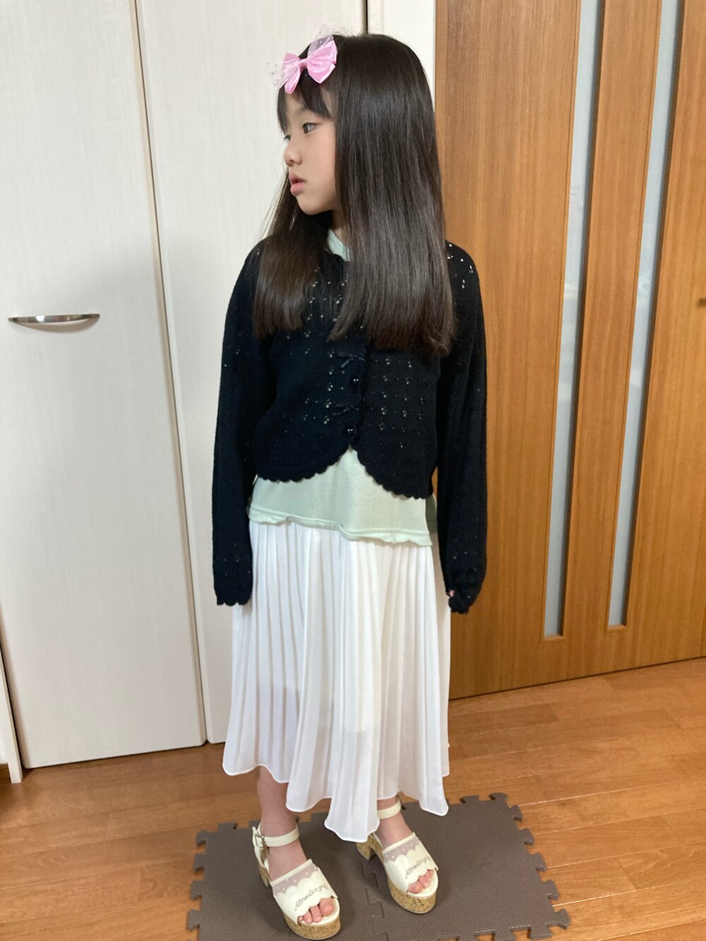 ブラック系のカーディガン/ボレロ、ホワイト系のワンピースを着用したキッズの春コーディネートの2枚目の写真