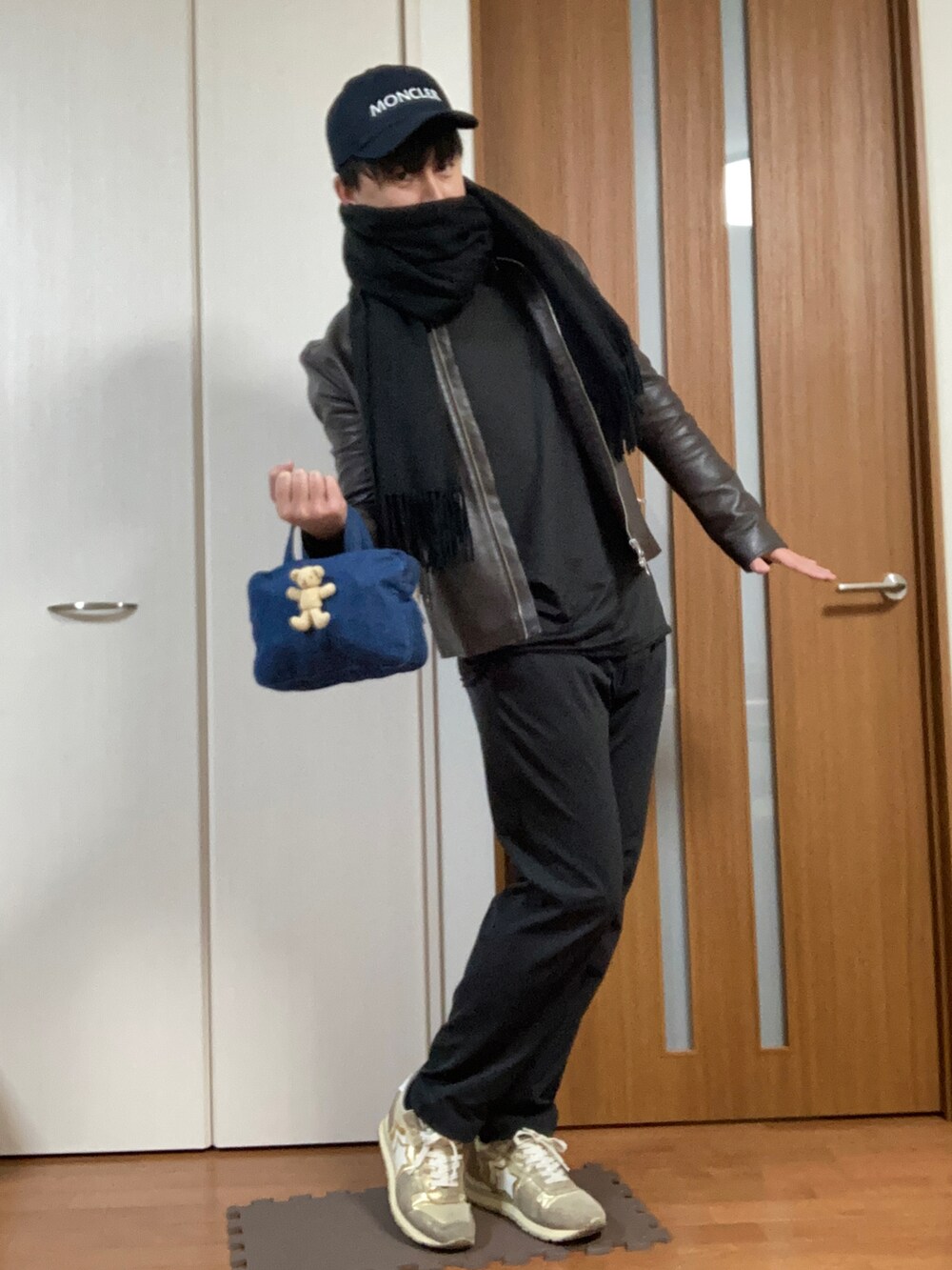 ゴールド系のスニーカー、ブラウン系のライダースジャケット、ブラック系のチノパンツを着用したメンズの冬コーディネートの2枚目の写真
