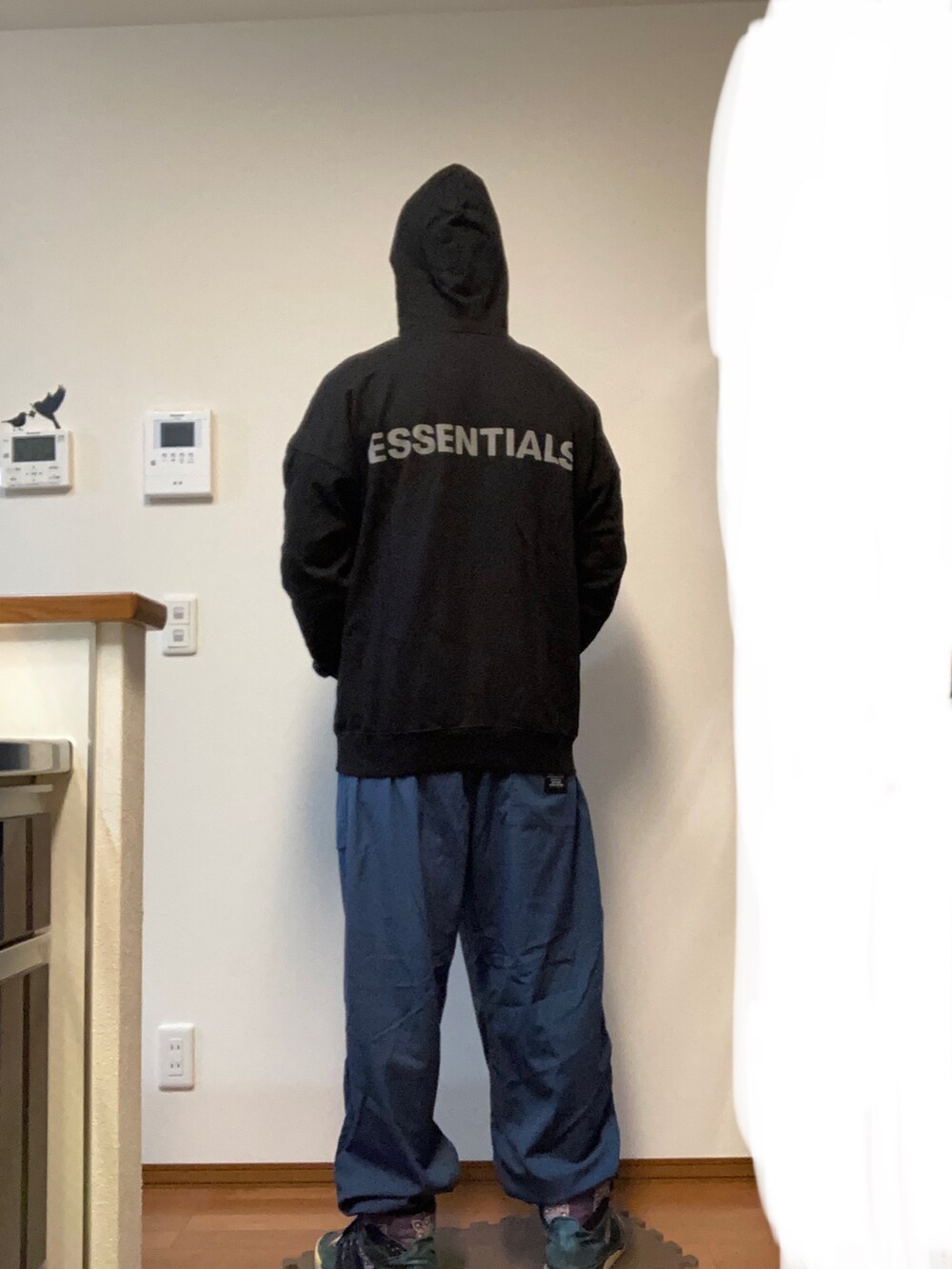 ブラック系のパーカー、ブルー系のカーゴパンツ、ブルー系のスニーカーを着用したメンズの秋コーディネートの2枚目の写真