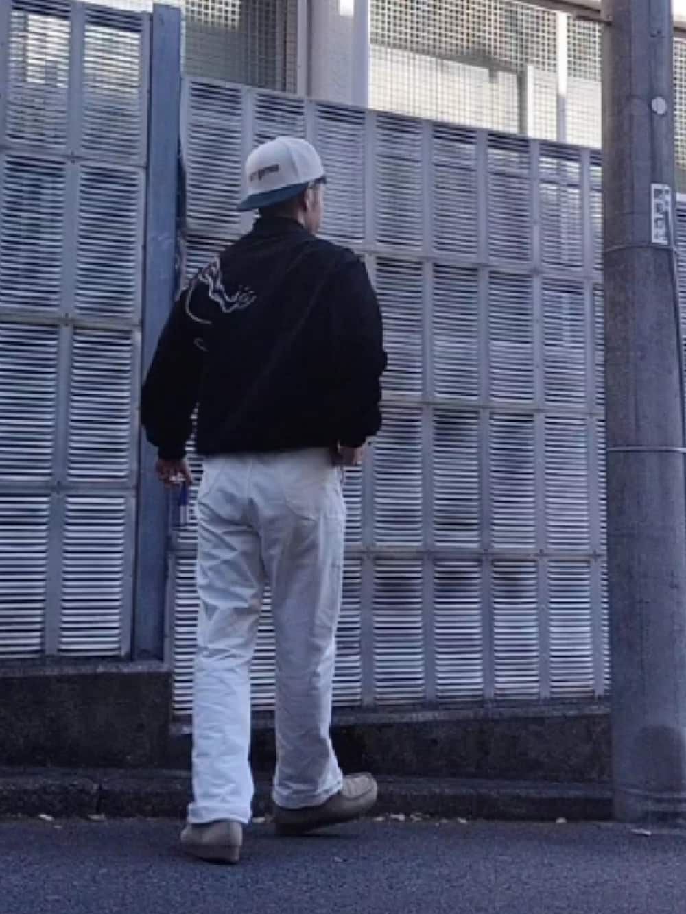 ホワイト系のデニムパンツ、ブラック系のスカジャン、ホワイト系のキャップを着用したメンズの秋コーディネートの4枚目の写真