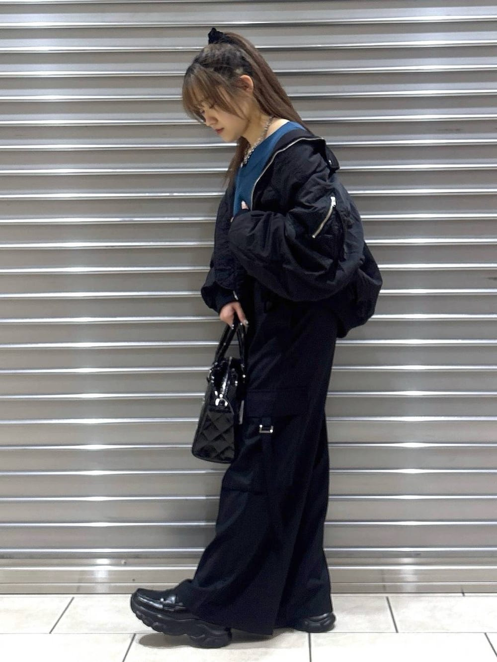 ブラック系のスラックス、グリーン系のニット/セーター、ブラック系のブルゾンを着用したレディースの秋コーディネートの2枚目の写真