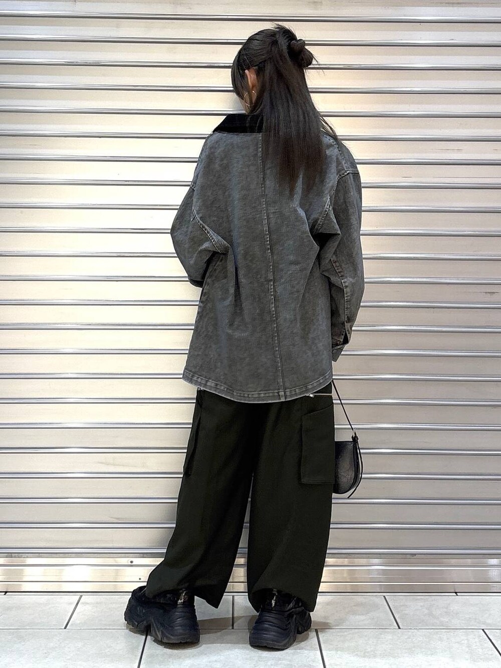 ブラック系のスニーカー、グリーン系のスラックス、ブラック系のハンドバッグを着用したレディースの春コーディネートの3枚目の写真