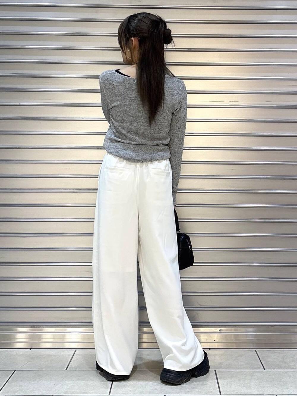 ブラック系のスニーカー、ブラック系のボストンバッグ、ブラック系のTシャツ/カットソーを着用したレディースの冬コーディネートの3枚目の写真