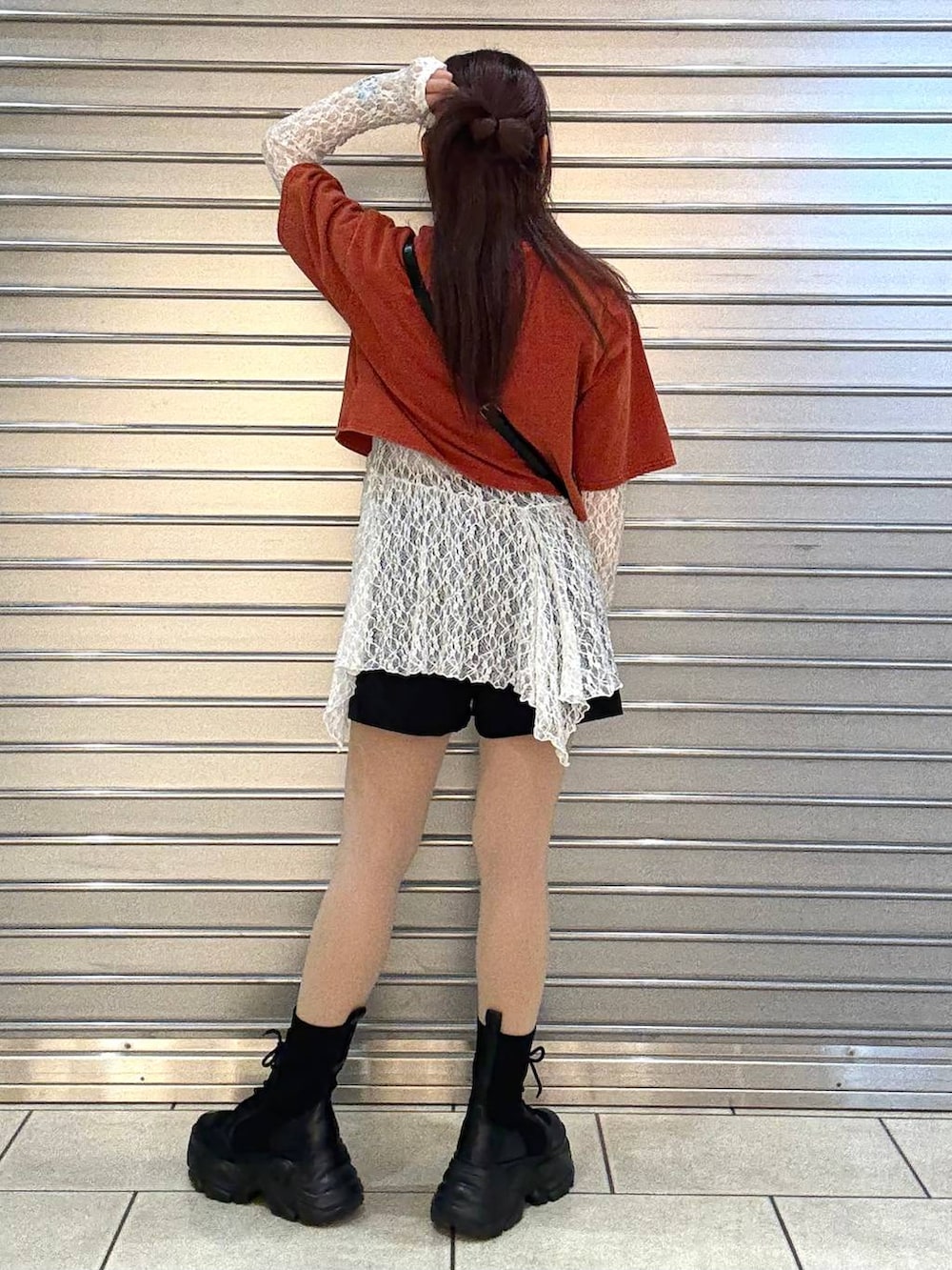 ブラック系のブーツ、ホワイト系のチュニック、ブラック系のショルダーバッグを着用したレディースの春コーディネートの3枚目の写真