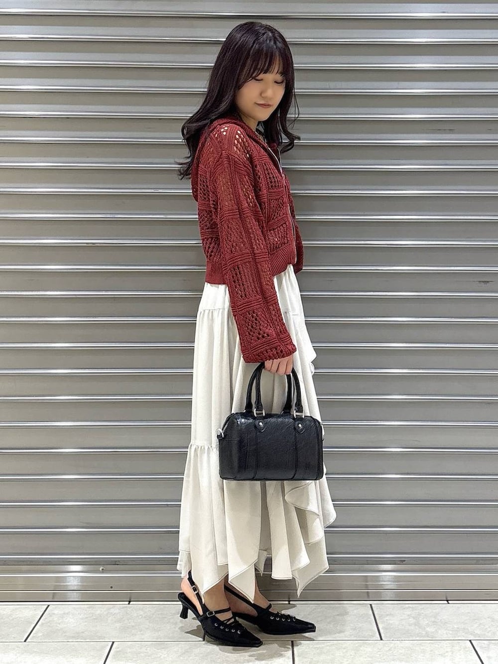 ブラック系のキャミソール、ベージュ系のスカート、ブラック系のボストンバッグを着用したレディースの春コーディネートの2枚目の写真