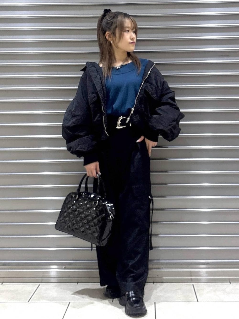 ブラック系のスラックス、グリーン系のニット/セーター、ブラック系のブルゾンを着用したレディースの秋コーディネートの4枚目の写真