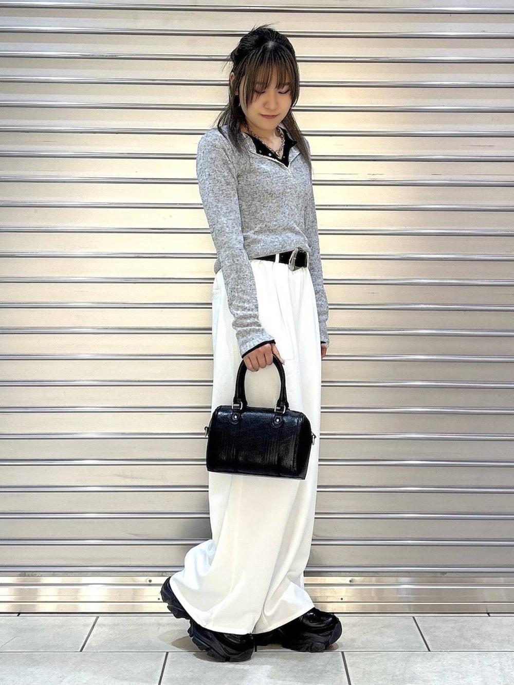 ブラック系のスニーカー、ブラック系のボストンバッグ、ブラック系のTシャツ/カットソーを着用したレディースの冬コーディネートの2枚目の写真