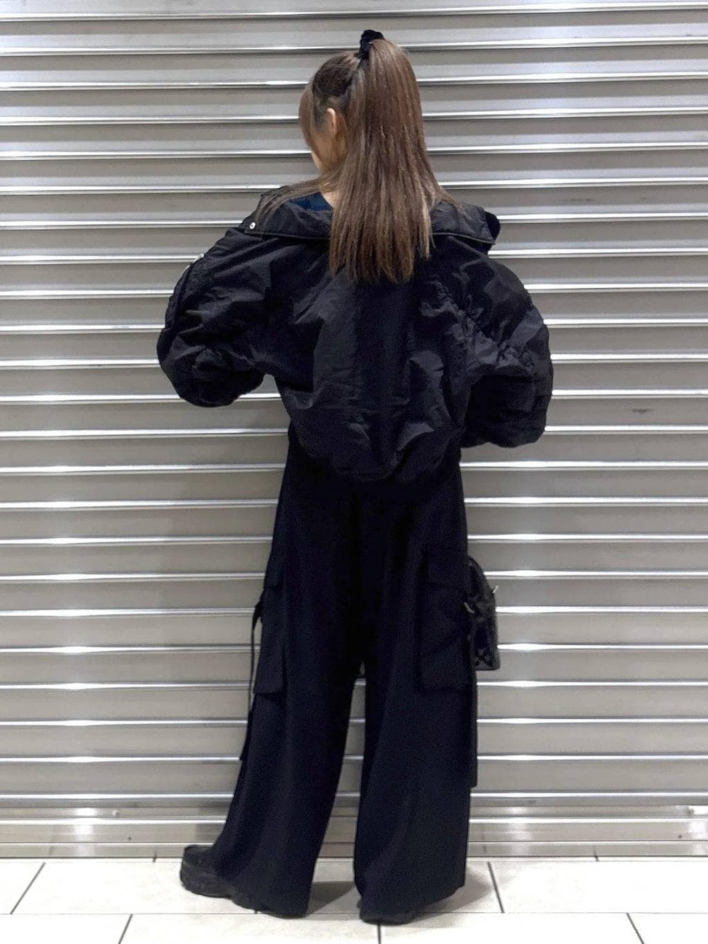 ブラック系のスラックス、グリーン系のニット/セーター、ブラック系のブルゾンを着用したレディースの秋コーディネートの3枚目の写真