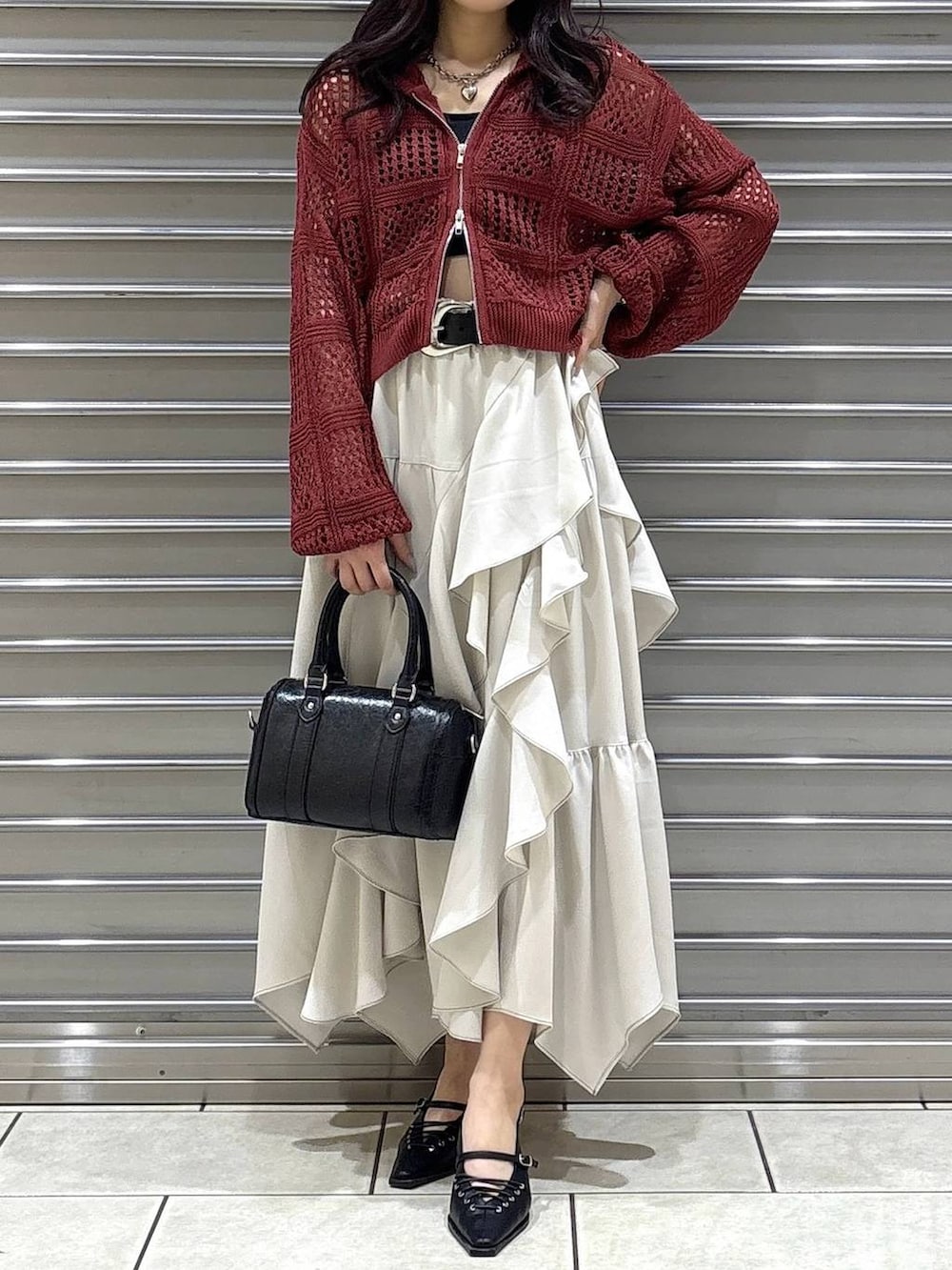 ブラック系のキャミソール、ベージュ系のスカート、ブラック系のボストンバッグを着用したレディースの春コーディネートの4枚目の写真