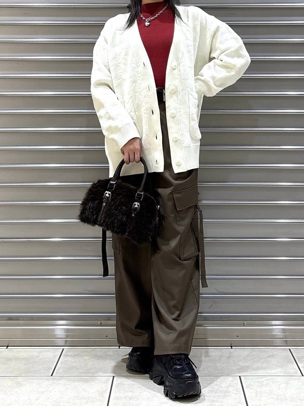 ブラック系のスニーカー、ブラウン系のスラックス、ホワイト系のカーディガン/ボレロを着用したレディースの冬コーディネートの4枚目の写真
