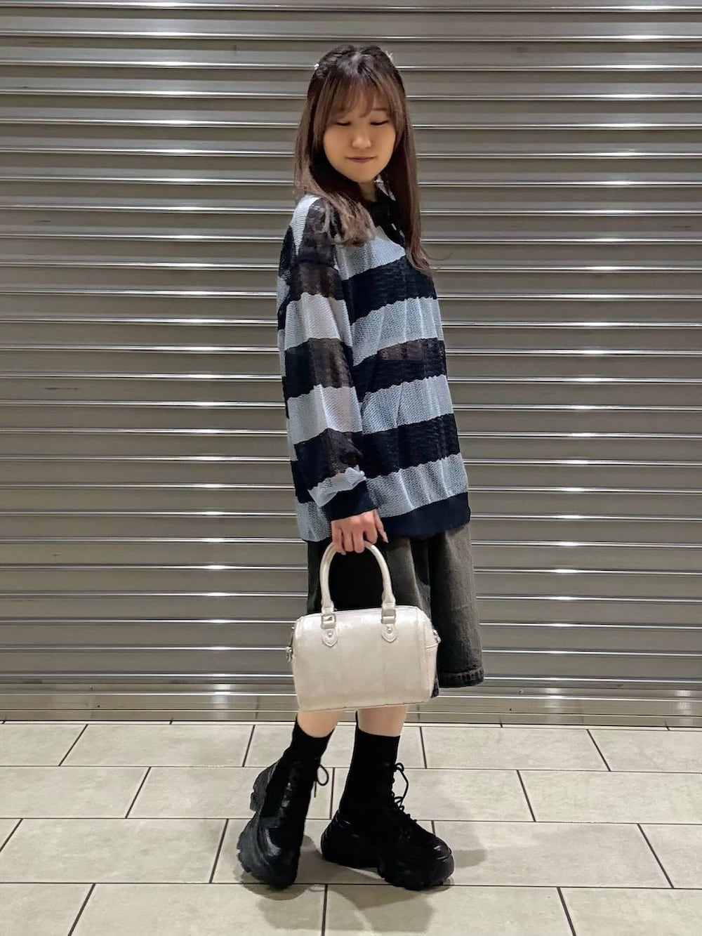 ブラック系のブーツ、ブラック系のキャミソール、ホワイト系のボストンバッグを着用したレディースの春コーディネートの2枚目の写真