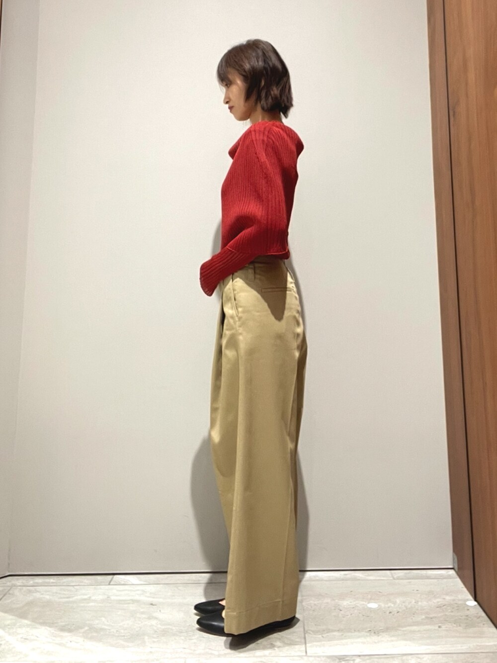 オレンジ系のニット/セーター、ベージュ系のその他パンツを着用したレディースの秋コーディネートの6枚目の写真