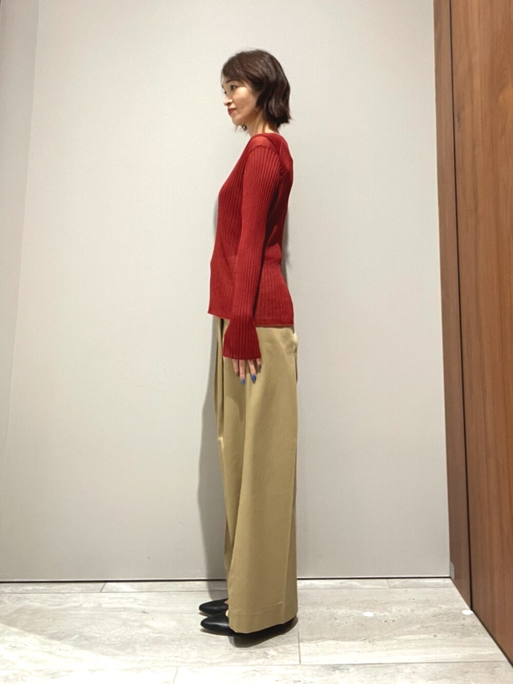 オレンジ系のニット/セーター、ベージュ系のその他パンツを着用したレディースの秋コーディネートの5枚目の写真