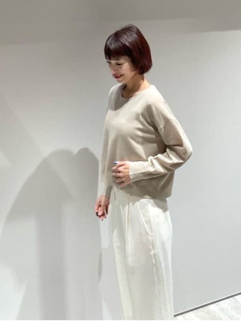 ベージュ系のニット/セーター、ホワイト系のスラックス、ゴールド系のネックレスを着用したレディースの秋コーディネートの4枚目の写真