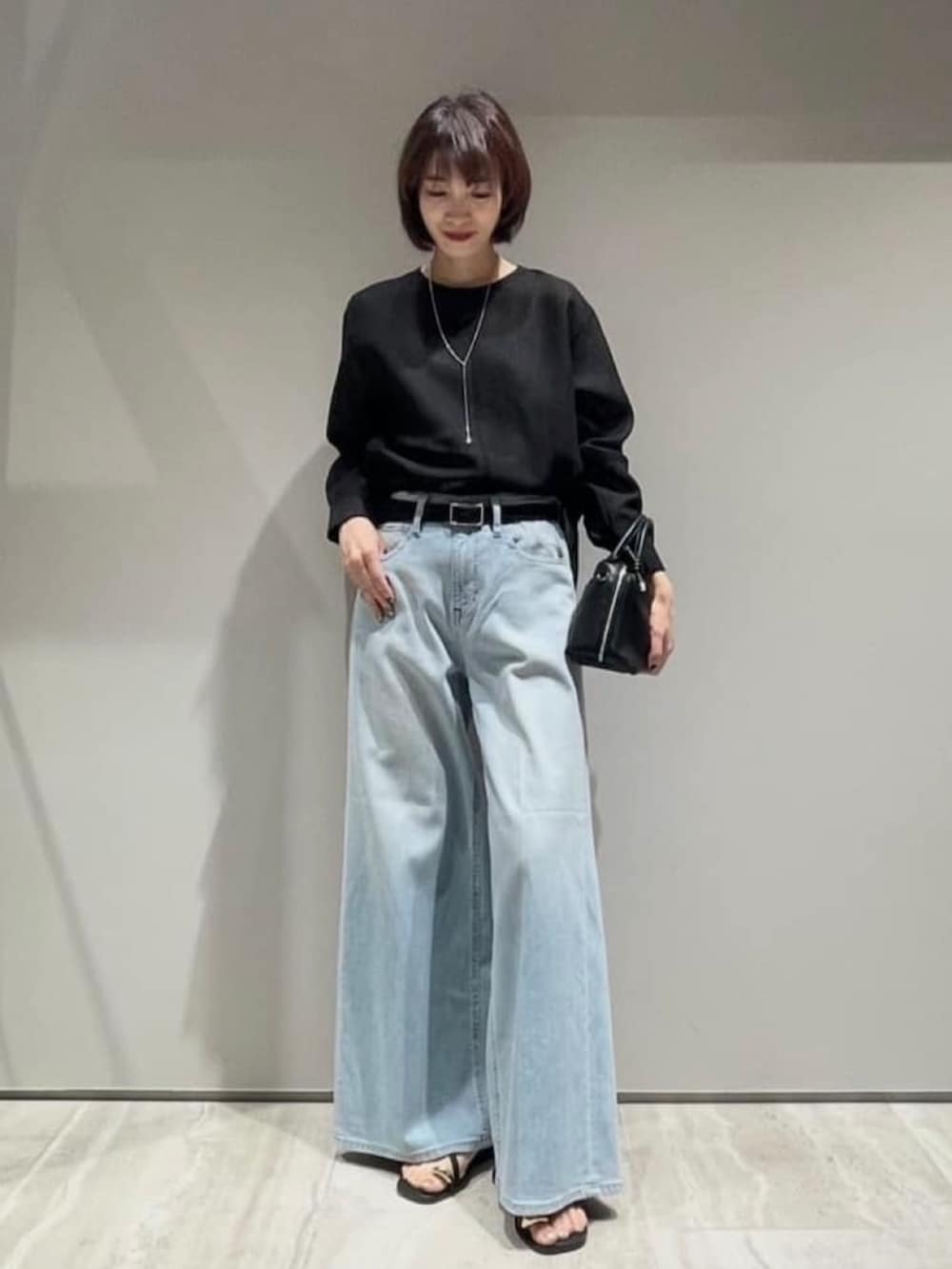 ブルー系のデニムパンツ、ブラック系のシャツ/ブラウス、ブラック系のベルトを着用したレディースの春コーディネートの2枚目の写真