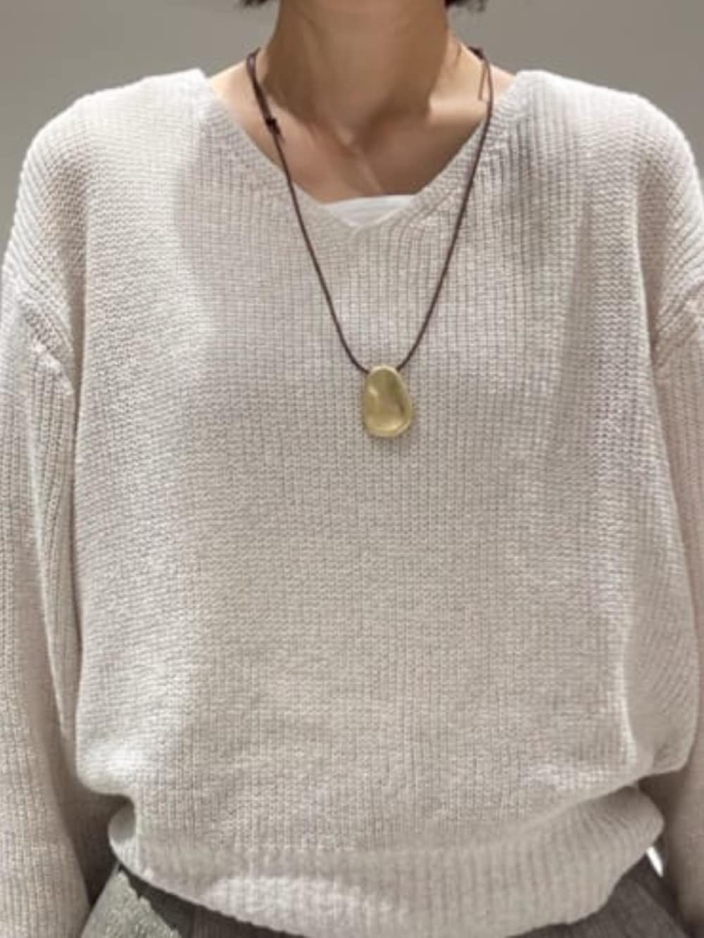 グレー系のその他パンツ、ベージュ系のニット/セーター、ホワイト系のタンクトップを着用したレディースの春コーディネートの2枚目の写真