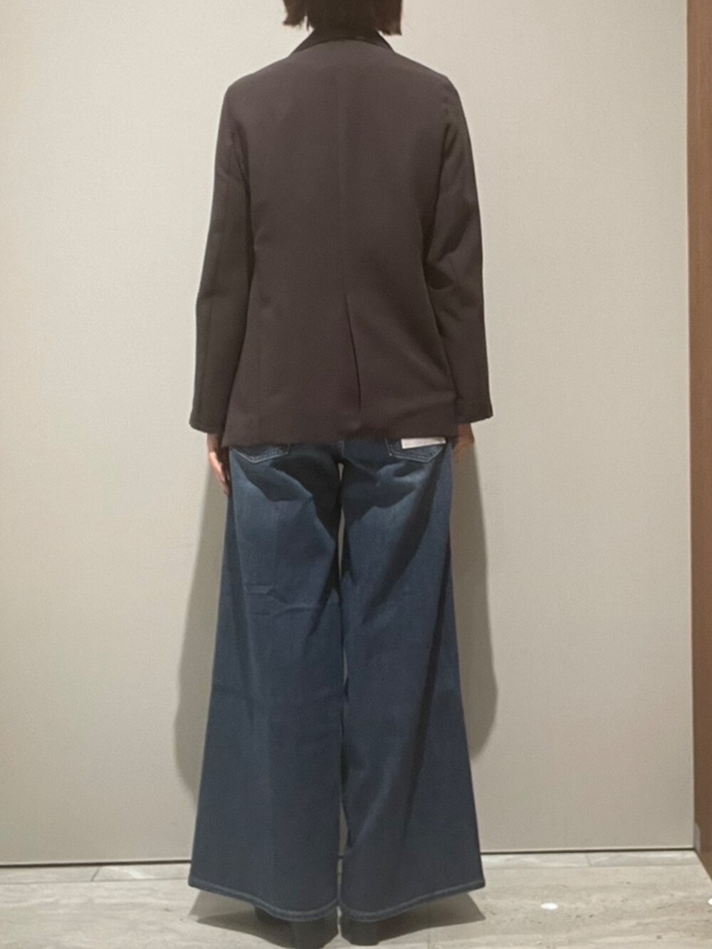 ブルー系のデニムパンツ、ブラウン系のショルダーバッグ、ブラウン系のテーラードジャケットを着用したレディースの秋コーディネートの4枚目の写真