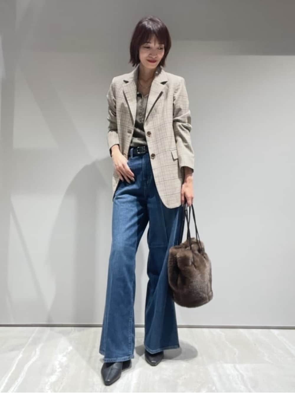 ブラウン系のニット/セーター、ベージュ系のテーラードジャケット、ブラウン系のショルダーバッグを着用したレディースの秋コーディネートの2枚目の写真