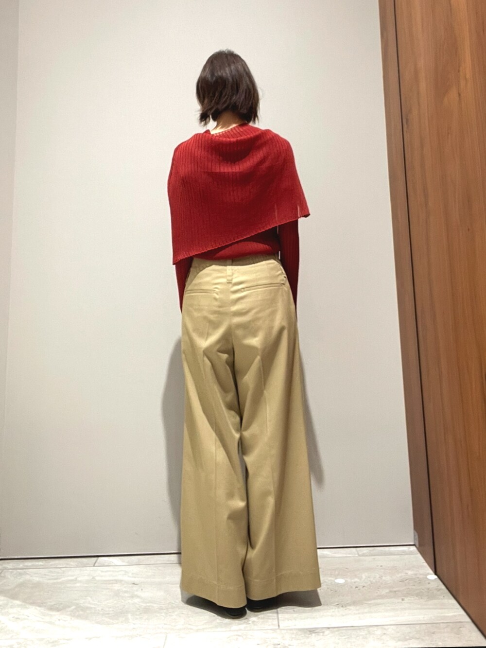 オレンジ系のニット/セーター、ベージュ系のその他パンツを着用したレディースの秋コーディネートの7枚目の写真