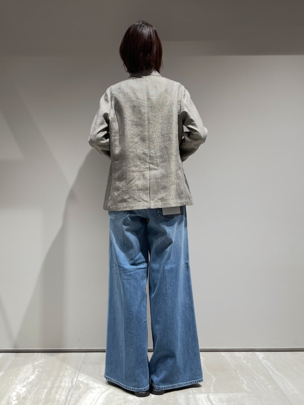 ブルー系のデニムパンツ、ベージュ系のテーラードジャケット、ホワイト系のタンクトップを着用したレディースの春コーディネートの7枚目の写真