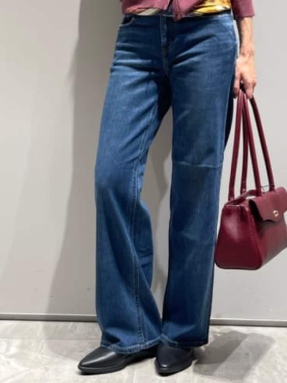 ブルー系のデニムパンツ、レッド系のカーディガン/ボレロ、ゴールド系のネックレスを着用したレディースの秋コーディネートの5枚目の写真