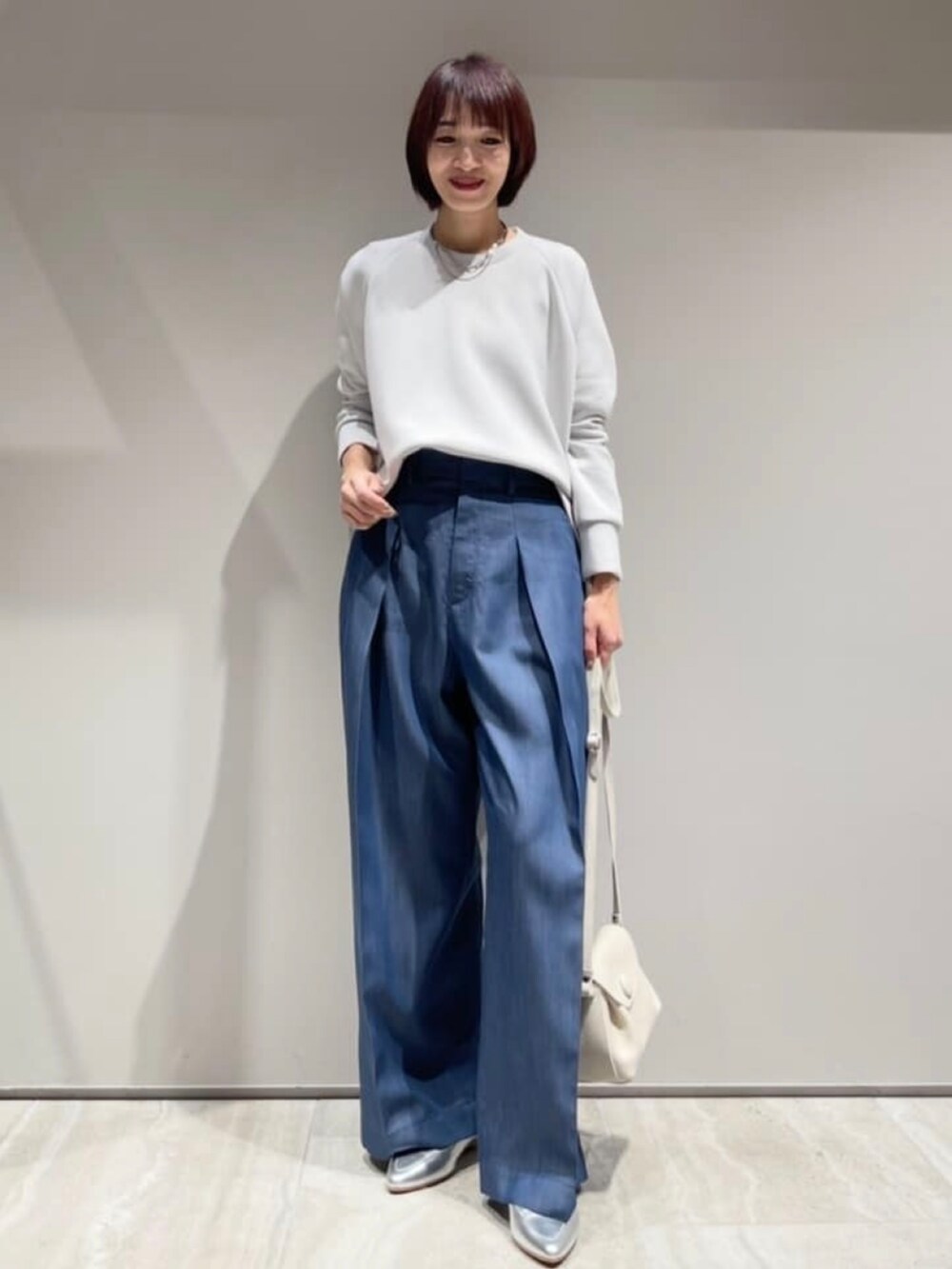 ホワイト系のショルダーバッグ、グレー系のスウェット、ブルー系のその他パンツを着用したレディースの冬コーディネートの2枚目の写真