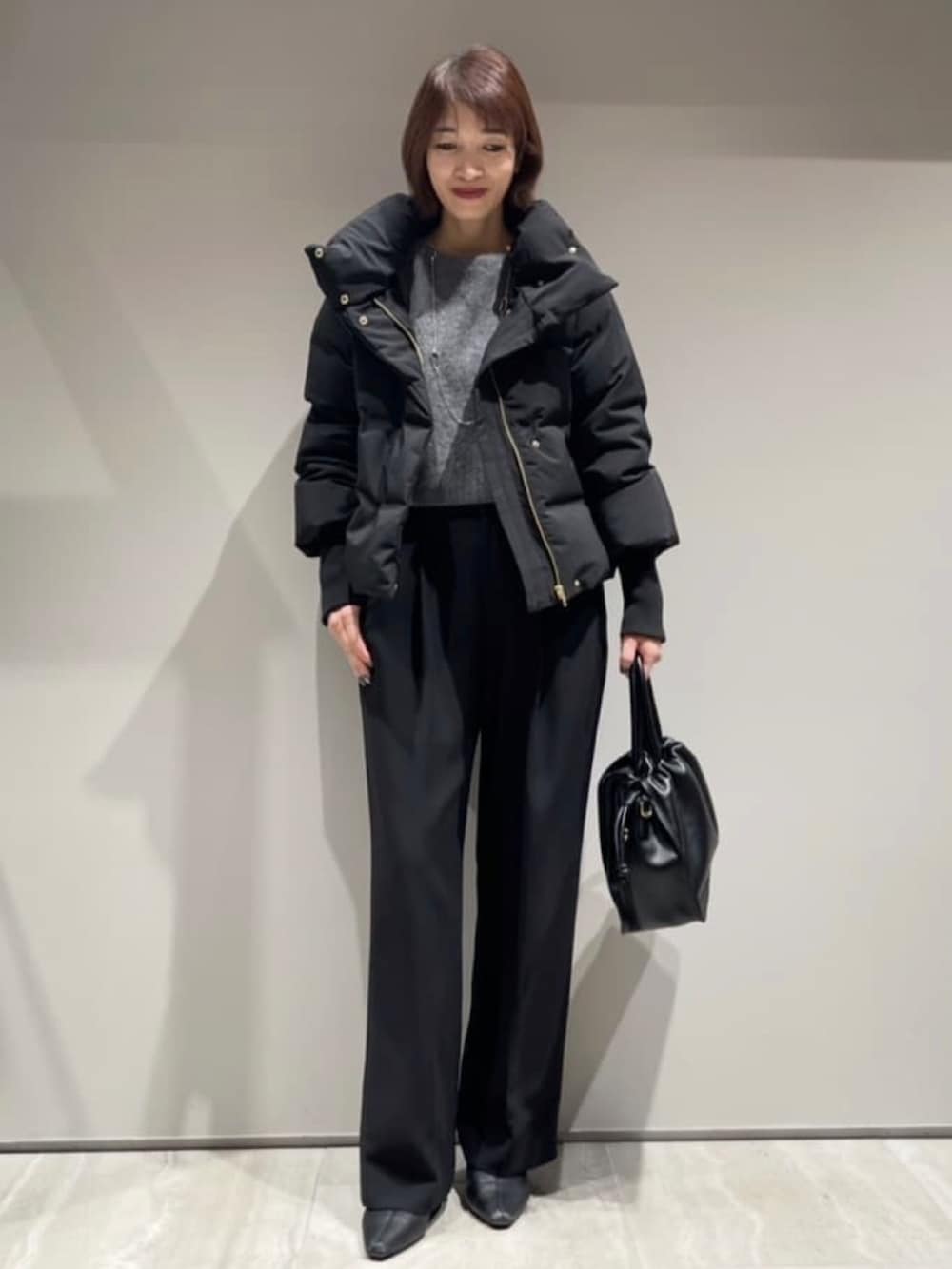 ブラック系のその他パンツ、ブラック系のダウンジャケット/コート、グレー系のニット/セーターを着用したレディースの冬コーディネートの2枚目の写真