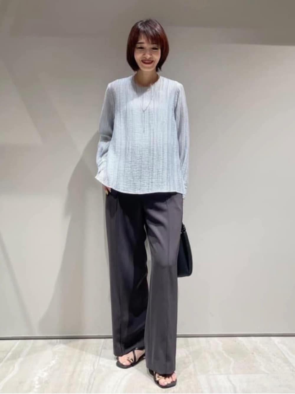 ブルー系のシャツ/ブラウス、グレー系のその他パンツ、シルバー系のネックレスを着用したレディースの春コーディネートの2枚目の写真