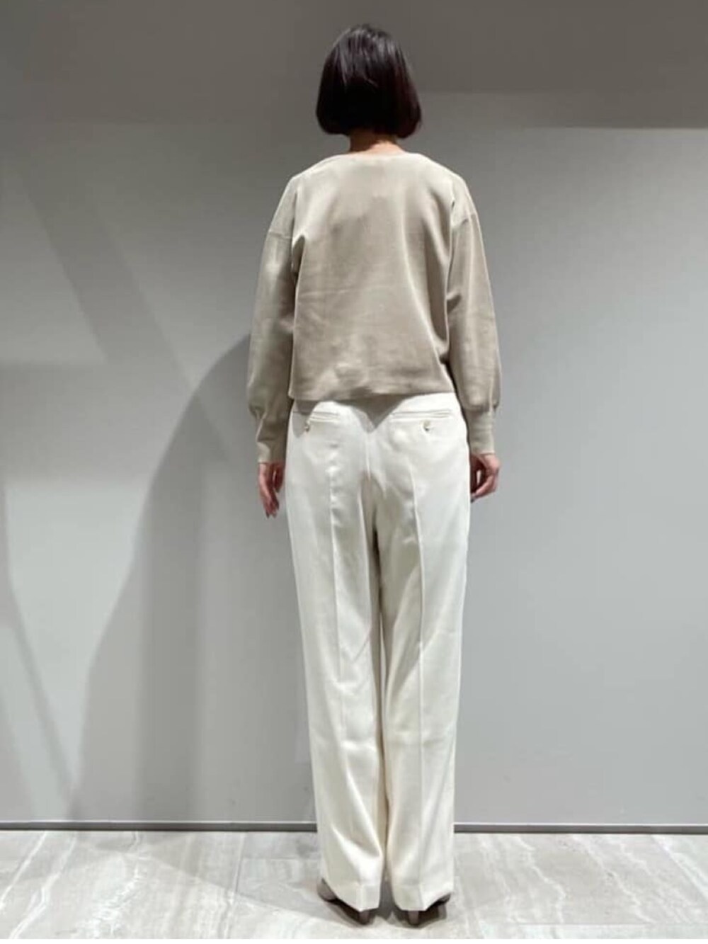 ベージュ系のニット/セーター、ホワイト系のスラックス、ゴールド系のネックレスを着用したレディースの秋コーディネートの6枚目の写真