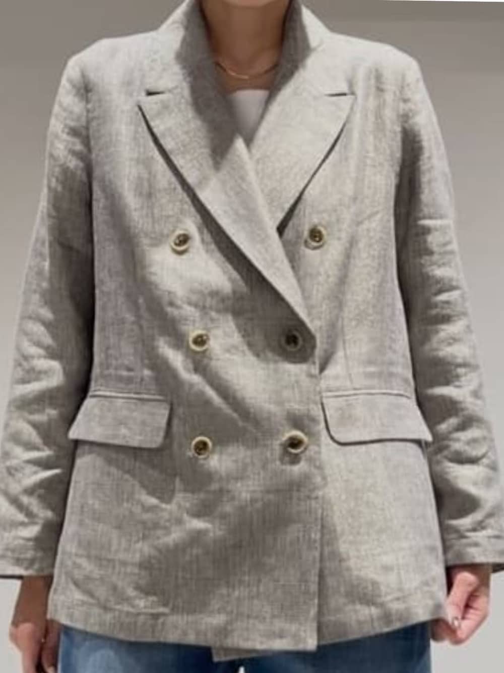 ブルー系のデニムパンツ、ベージュ系のテーラードジャケット、ホワイト系のタンクトップを着用したレディースの春コーディネートの3枚目の写真