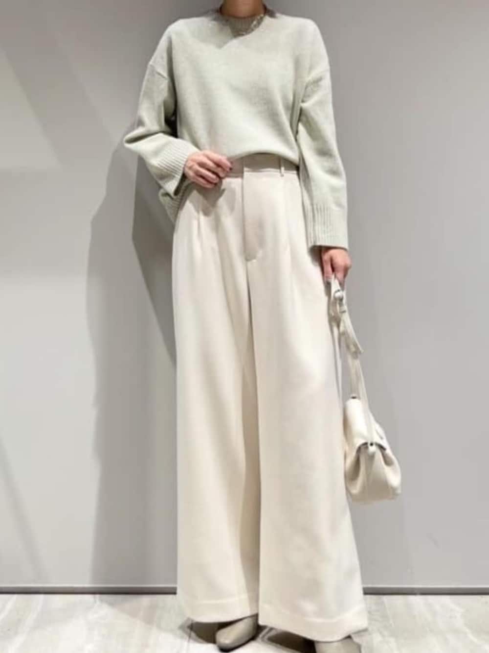 ホワイト系のその他パンツ、グリーン系のニット/セーター、ホワイト系のショルダーバッグを着用したレディースの冬コーディネートの2枚目の写真